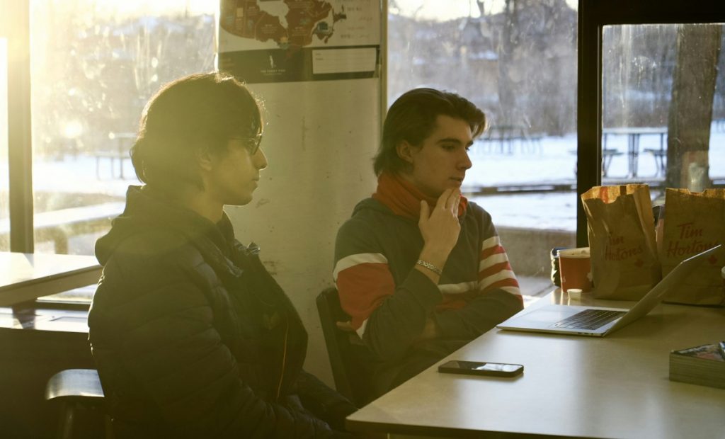 Two colleagues working together at a table in front of a laptop in Toronto