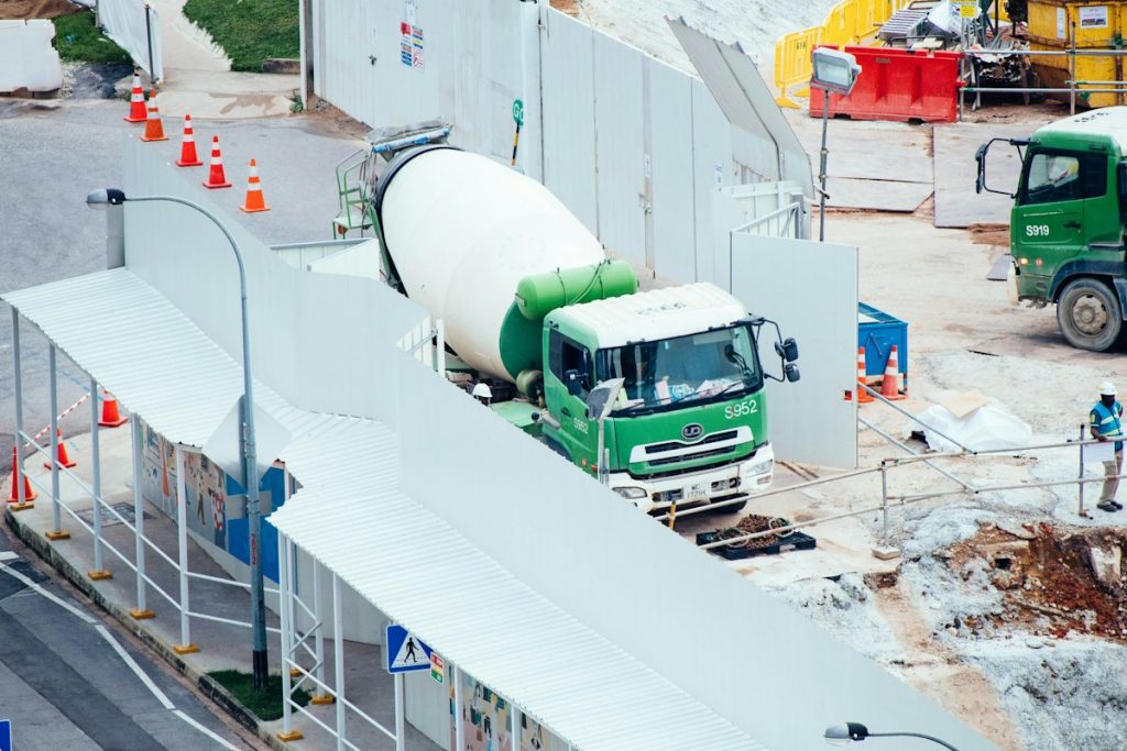 A green and white concrete mixer truck at a construction site