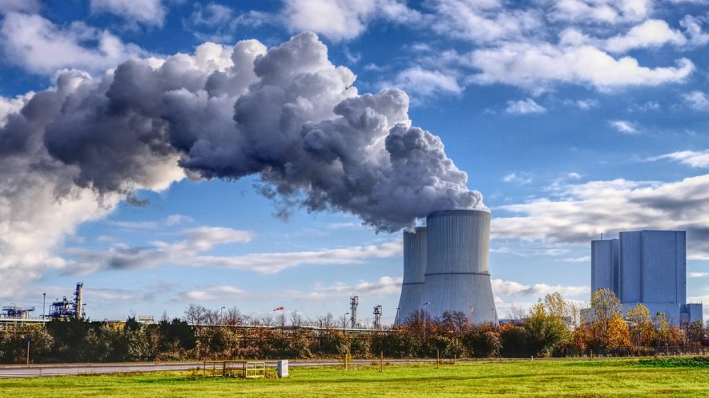 Industrial smokestacks releasing emissions against a blue sky