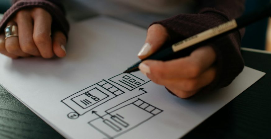 Hands sketching an app wireframe on paper