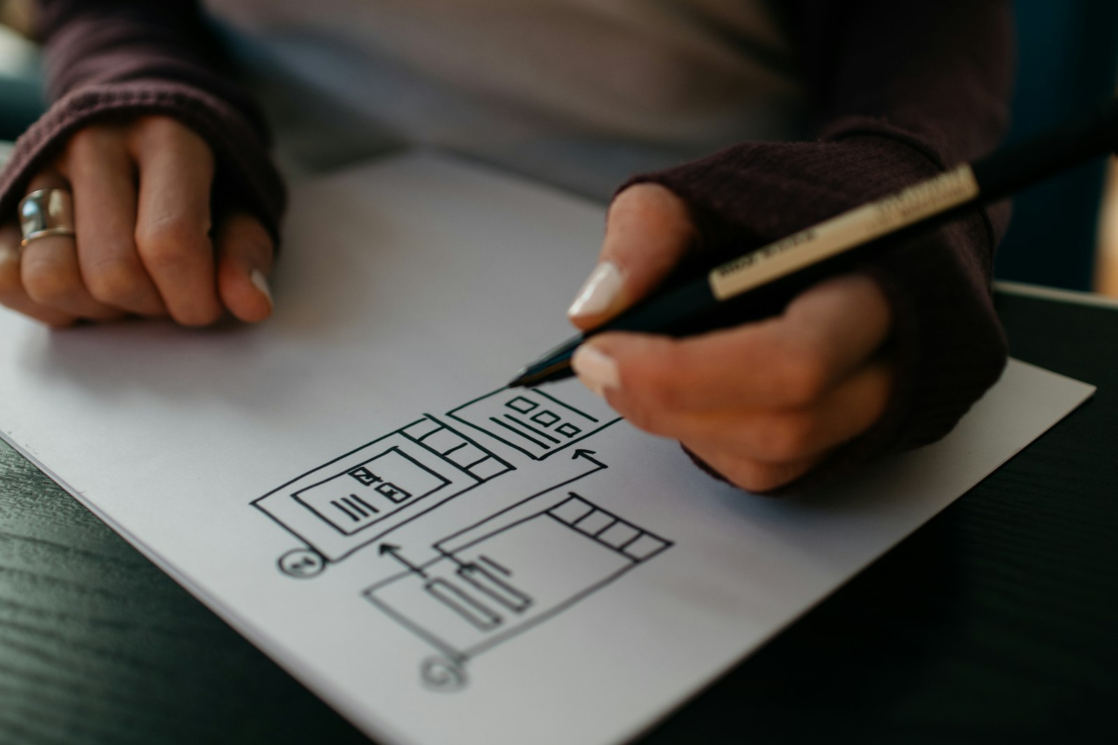 Hands sketching an app wireframe on paper