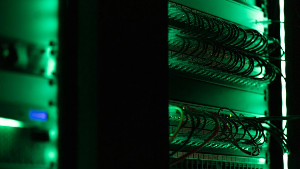 Rack of server hardware with status lights in a dark server room