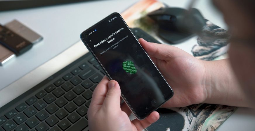 Close-up of a hand pressing a fingerprint sensor on a smartphone
