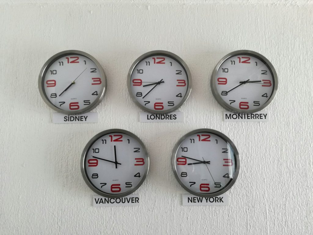 Wall clocks labelled London, Vancouver and New York showing different time zones