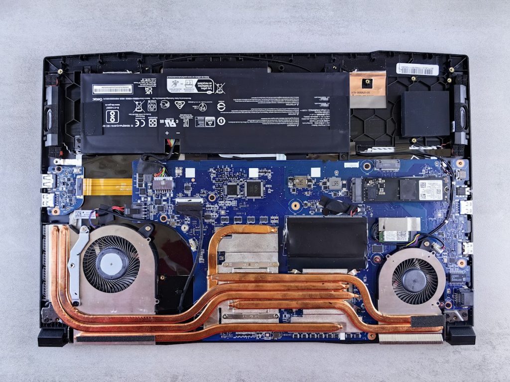 An opened laptop showing its motherboard, battery and cooling system during disassembly
