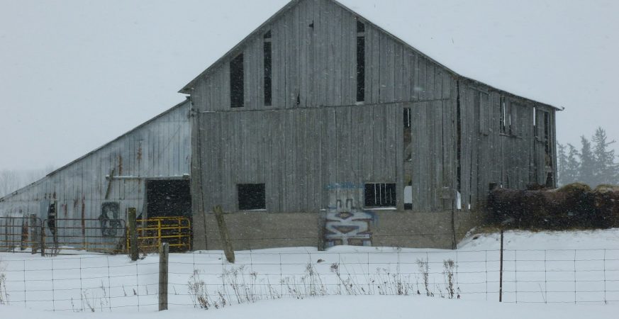 A barn standing alone in a snow-covered field in rural Ontario