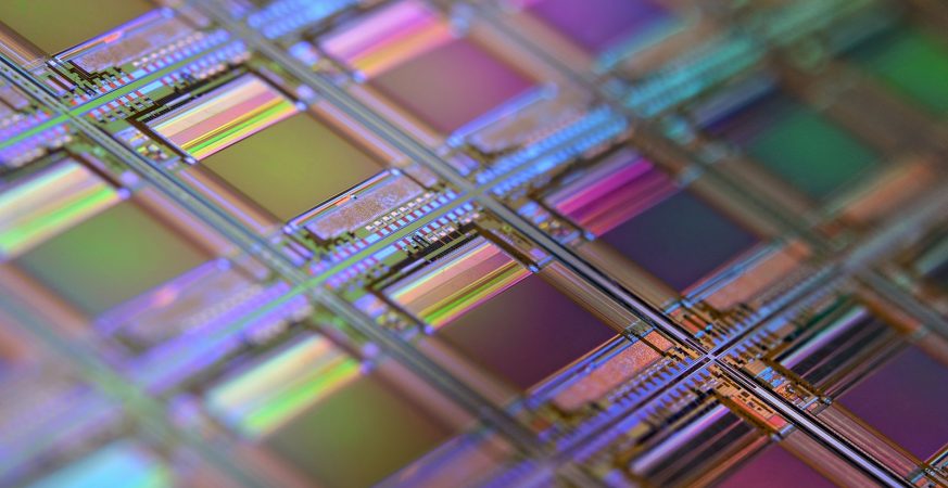 Close-up of an iridescent silicon wafer covered in a grid of microchip dies