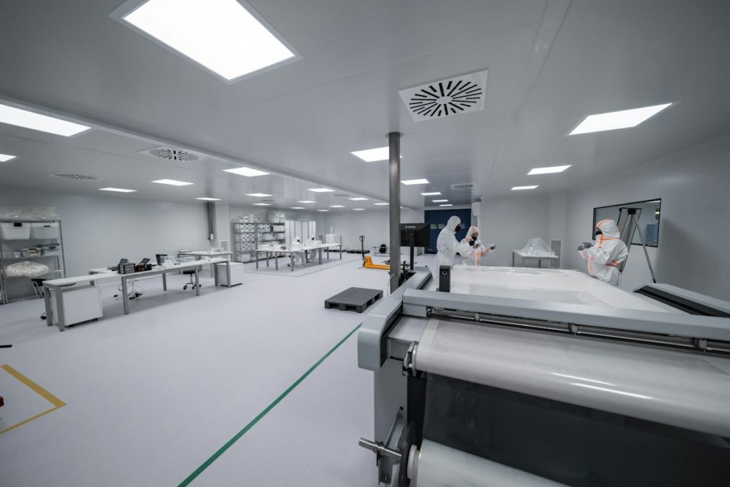 Operators in full protective suits working in a production clean room with manufacturing machinery