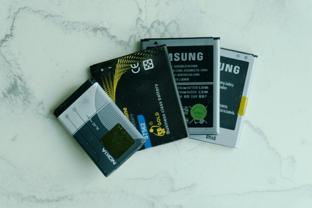 Several old lithium-ion mobile phone batteries laid out on a white surface