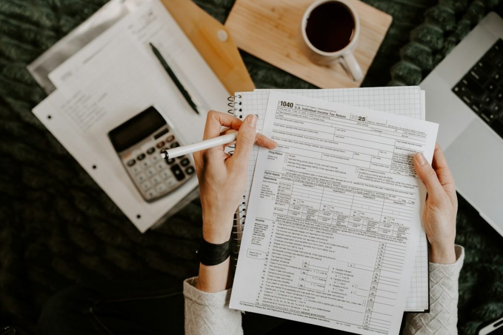 Person reviewing financial documents with a calculator and laptop