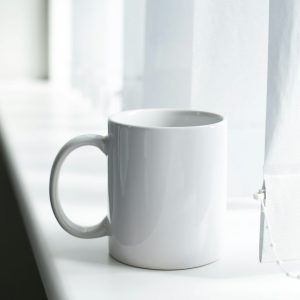 Plain white ceramic mug on an office window sill