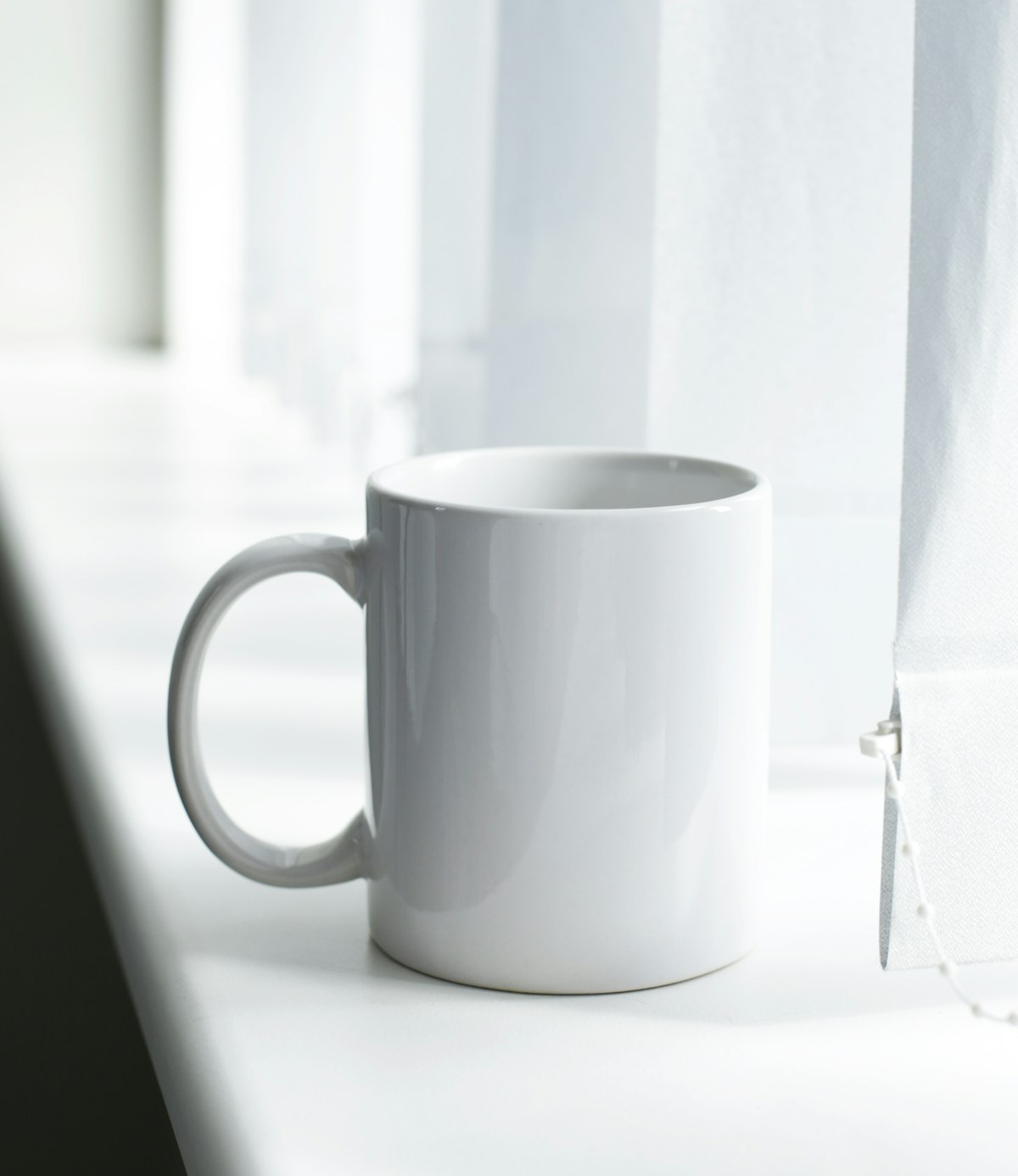 Plain white ceramic mug on an office window sill