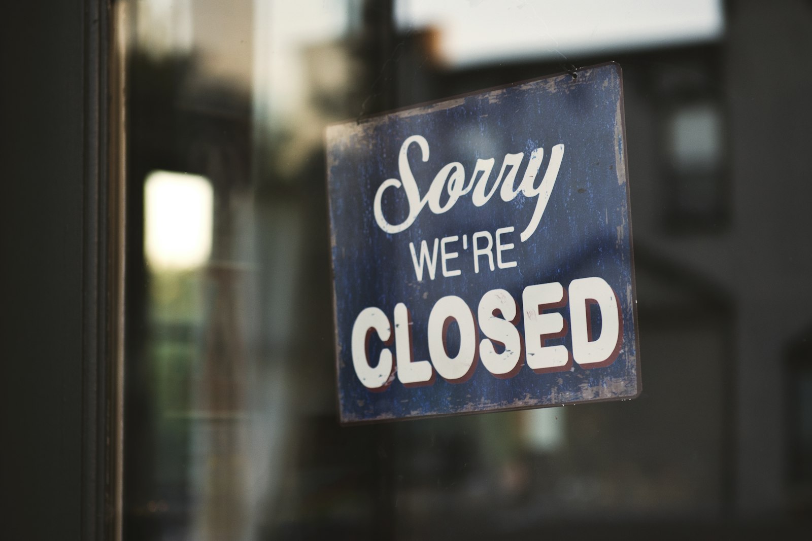A 'Sorry we're closed' sign hanging on a glass shop door