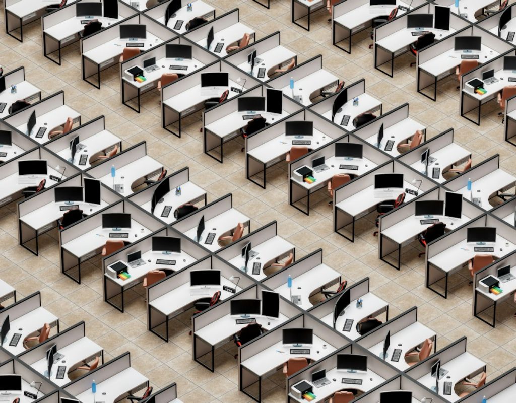 Open-plan office with rows of empty desks and computer monitors